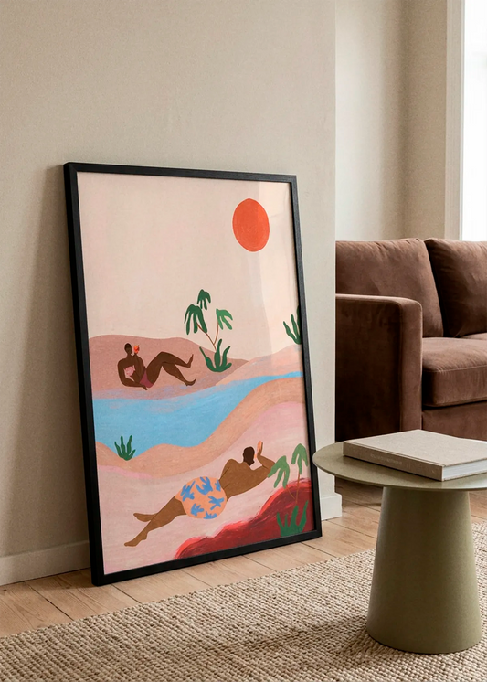 Beach Please by Arty Guava art print featuring two relaxed figures on a sunny beach with palm trees, soft blue water and a coral sun, displayed in a warm Scandinavian interior.