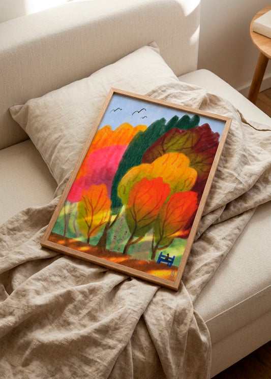 Cat On a Park Bench and Summer Trees by Dirkie Nell – framed colourful landscape poster with vivid orange, pink, green and burgundy trees, styled on a light sofa with soft neutral linen.