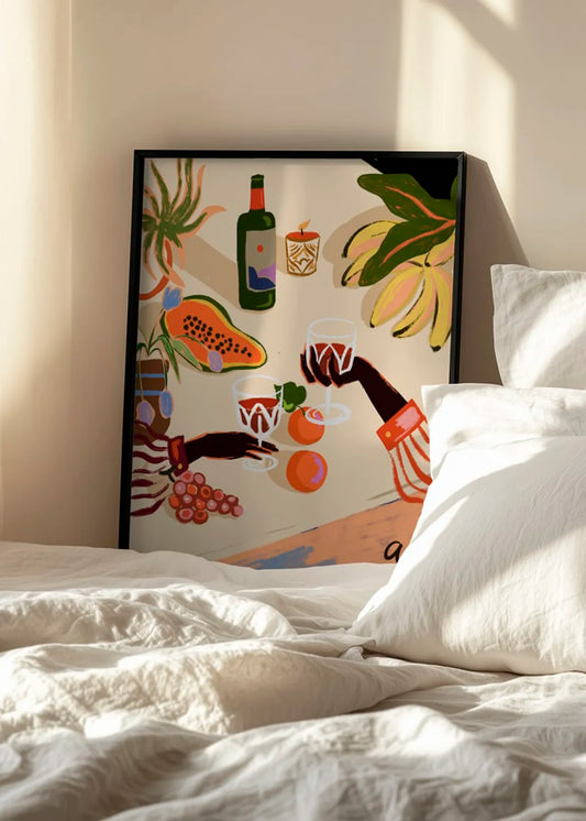 Indrammet farverig plakat med vin, frugt og skålende glas, stylet i et lyst soveværelse med hvidt sengetøj.