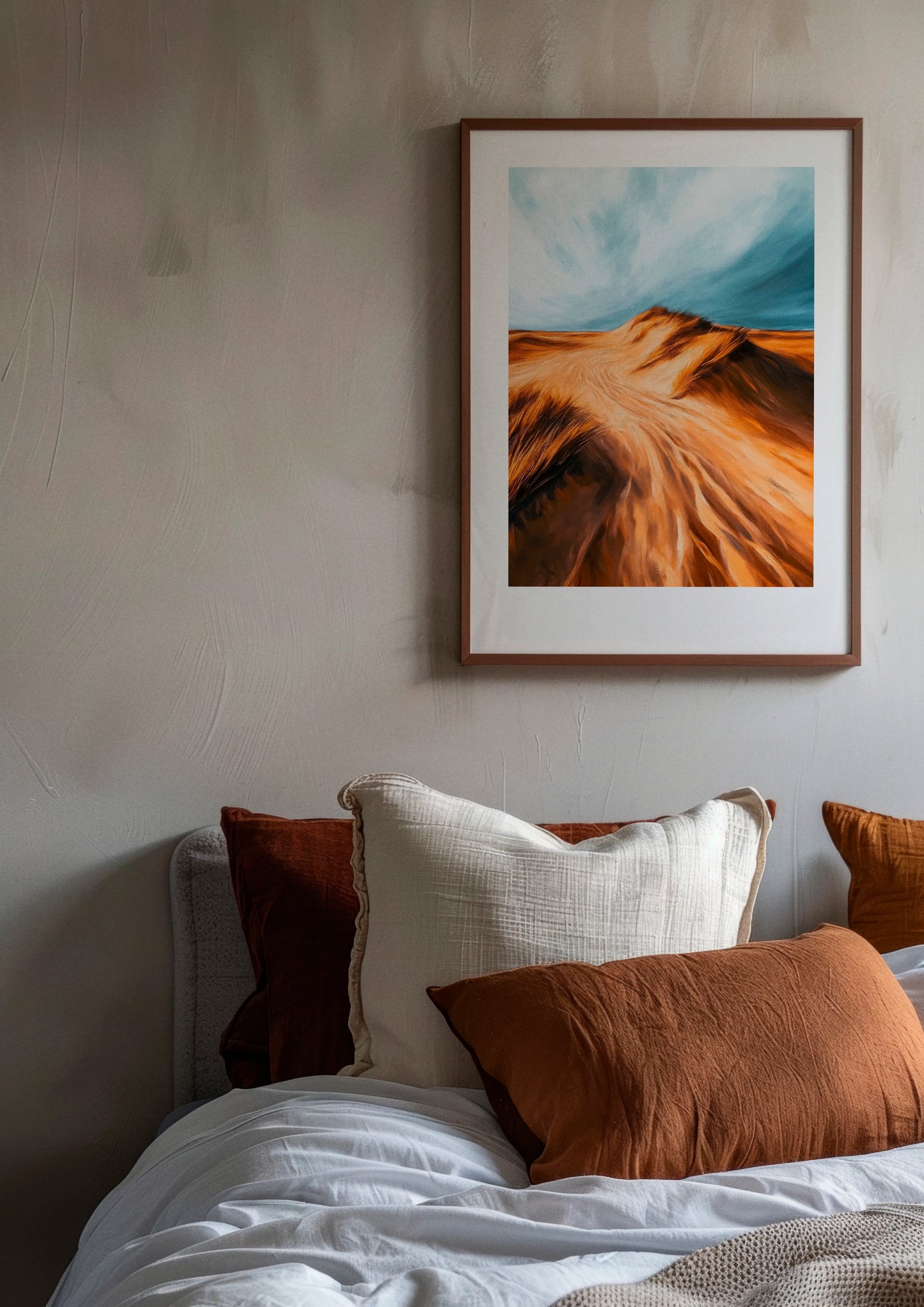 Dune poster by Hello Poster featuring golden sand dunes under a blue sky, displayed in a modern bedroom with neutral tones and warm textiles
