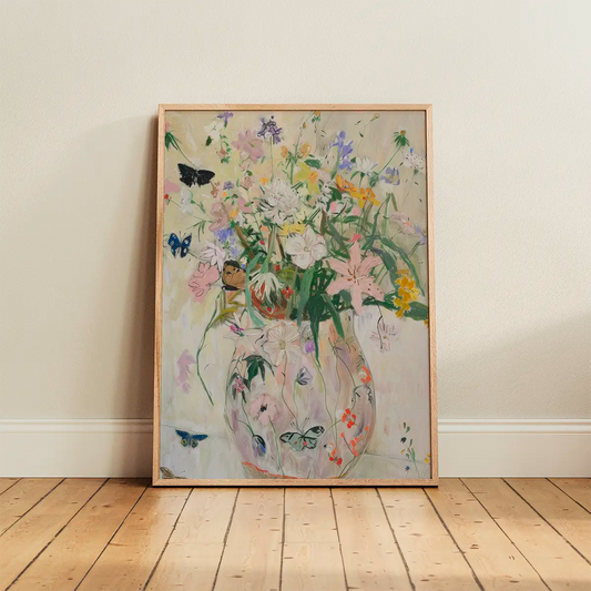 The ‘Wild Garden’ poster in an oak frame leaning against a light wall, featuring soft botanical and bird details in a Scandinavian interior
