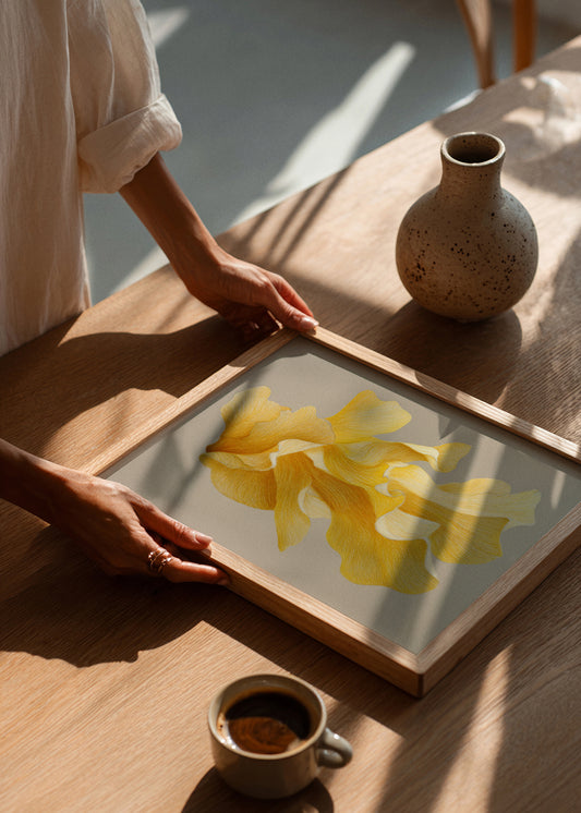 Plakaten Shape No. 60 fra Hello Poster i egetræsramme, lagt på træbord i sollys ved en kop kaffe – moderne og naturlig atmosfære.