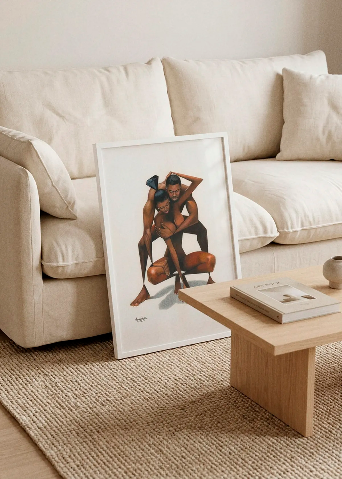 Abstract Loving Couple by Manasseh Johnson Sr. art print featuring two intertwined figures with geometric black shapes, displayed in a white frame leaning against a cream sofa in a warm Scandinavian living room.