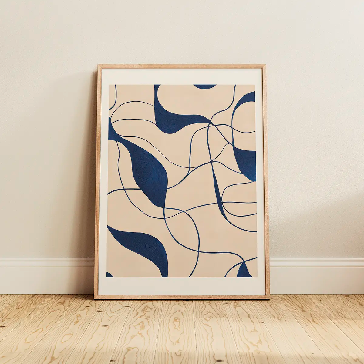 Abstract line-art poster with navy shapes on beige background, framed in oak and resting on light wooden floors, minimalist Scandinavian interior styling.