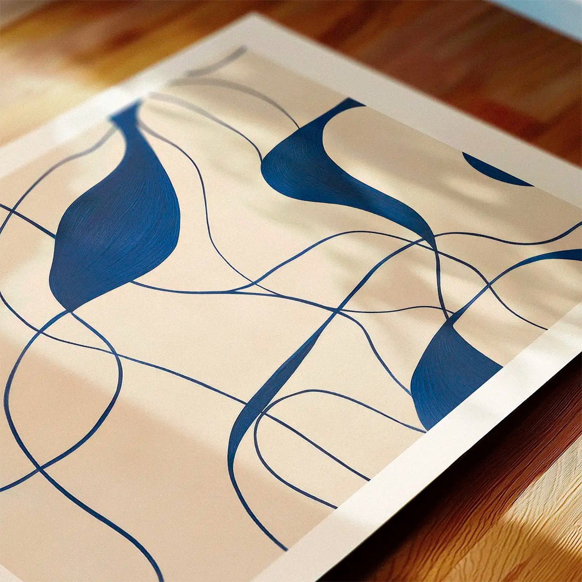 Abstract blue line-art poster with flowing shapes, photographed as a close-up on a wooden surface with soft daylight.