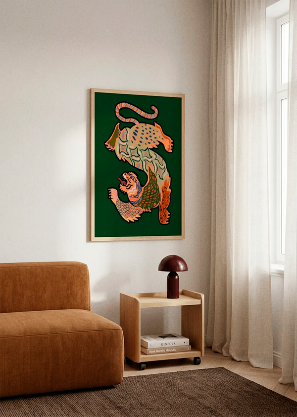 Asiantiger Green by Arty Guava displayed in a natural wood frame on a light wall beside a warm brown lounge chair and wooden side table in a calm, modern interior.