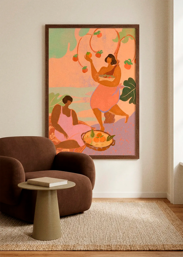Autumn by Arty Guava art print featuring two women harvesting persimmons in warm orange, pink and green tones, displayed in a dark wood frame in a calm Scandinavian living room.
