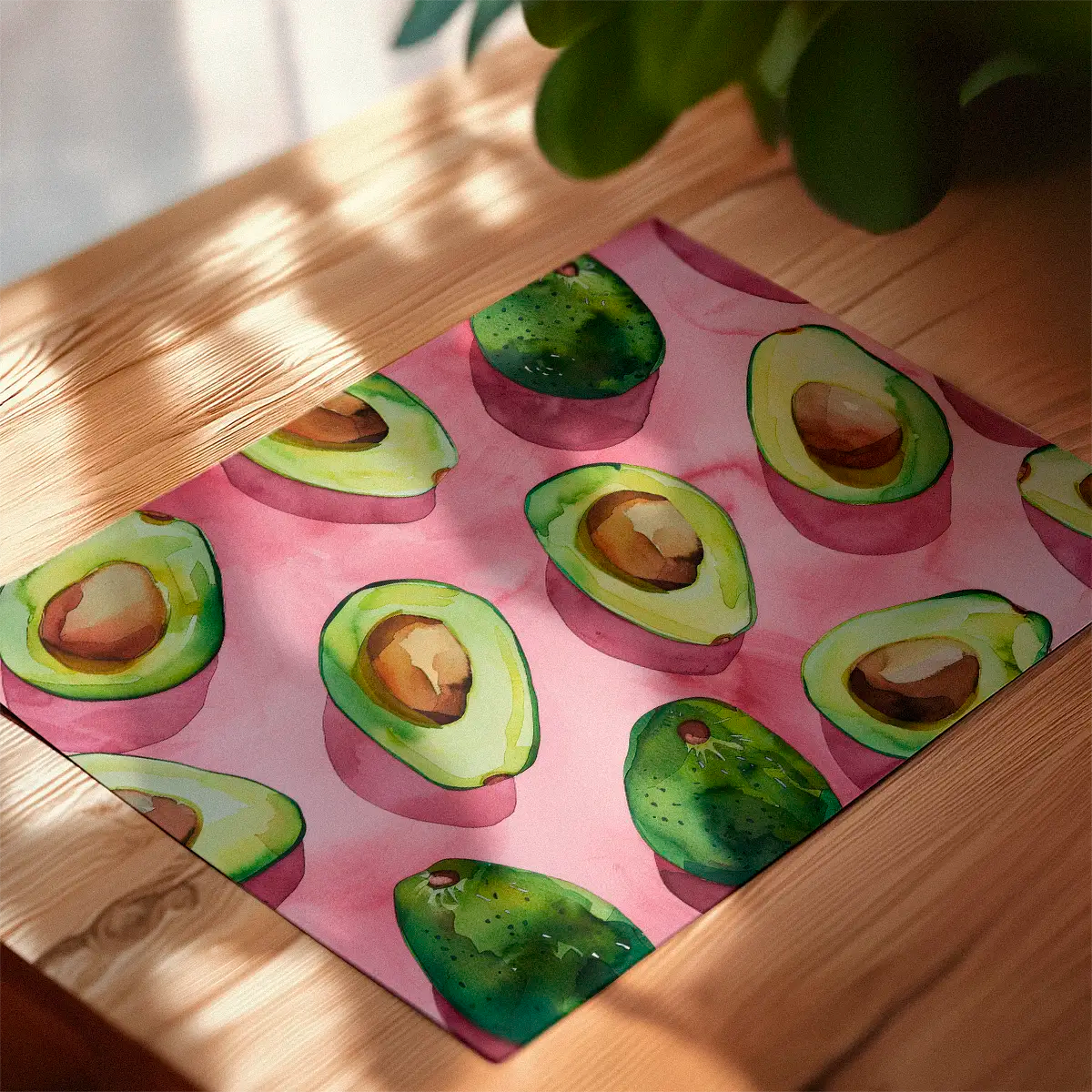 Avocado-themed art print lying flat on a wooden table with soft morning sunlight and shadows creating a cozy kitchen atmosphere.”