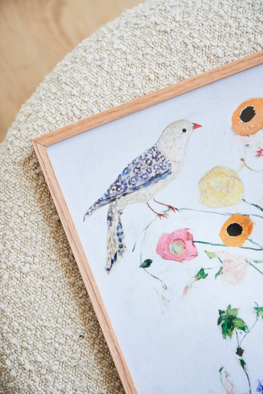 Close-up of the Bird no. 1 poster with a delicate bird and soft floral details, framed in light oak and styled on a textured surface