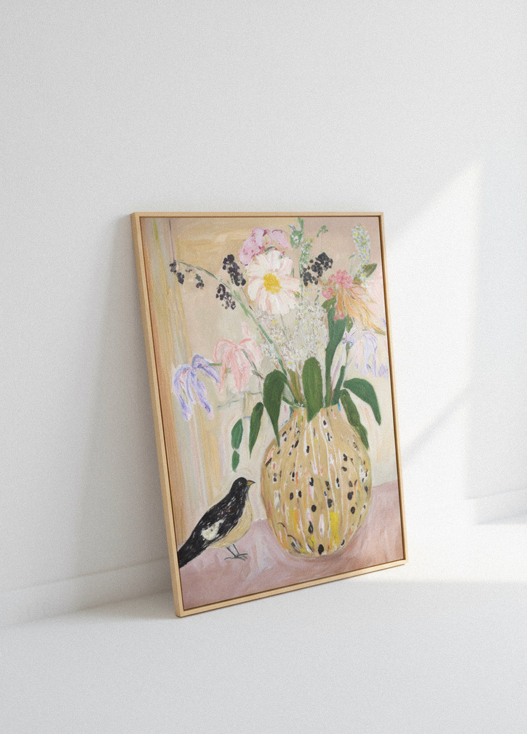 Framed “Bird No. 2” canvas leaning against a white wall, featuring a bird beside a yellow vase of wildflowers in soft pastel tones.