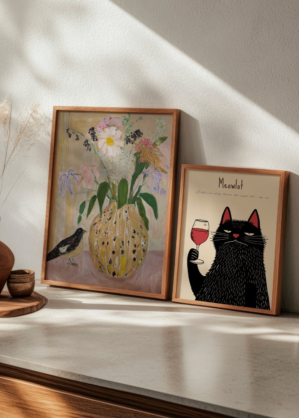 Contrasting HelloPoster prints: 'Bird no. 2', a soft floral still life, and 'Meowlot', a playful wine-loving black cat. Perfect for combining elegance and humor in your kitchen or hallway.