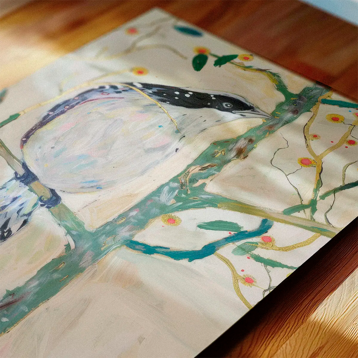 Pastel bird illustration ‘Bird No. 3’ shown lying on a wooden table with warm, soft sunlight and a calm Scandinavian atmosphere.