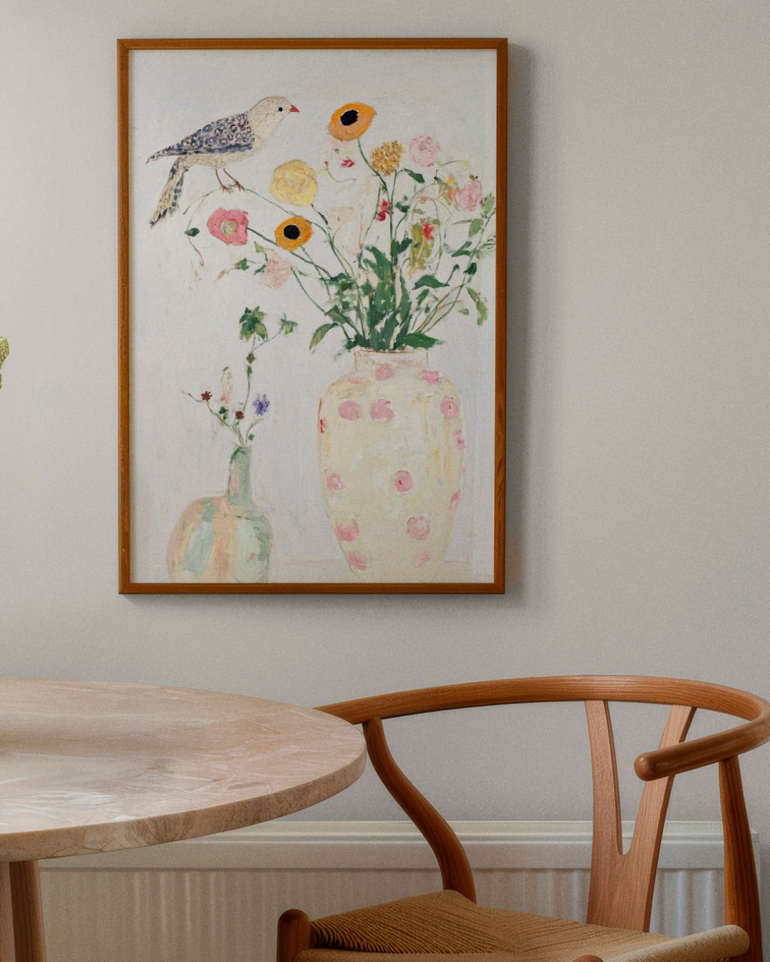 Soft, airy floral poster with a bird, framed in oak and hanging above a dining table and wooden chair in a light Scandinavian interior.