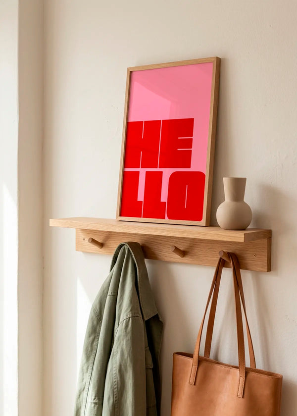 Bold Hello Typography by Athene Fritsch – framed pink and red typographic art poster with the word HELLO, styled on a natural wood shelf in a warm neutral hallway.