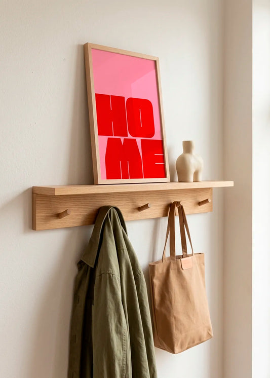 Bold Home Message by Athene Fritsch – framed pink and red typographic art poster with the word HOME, styled on a natural wood shelf in a warm neutral hallway.