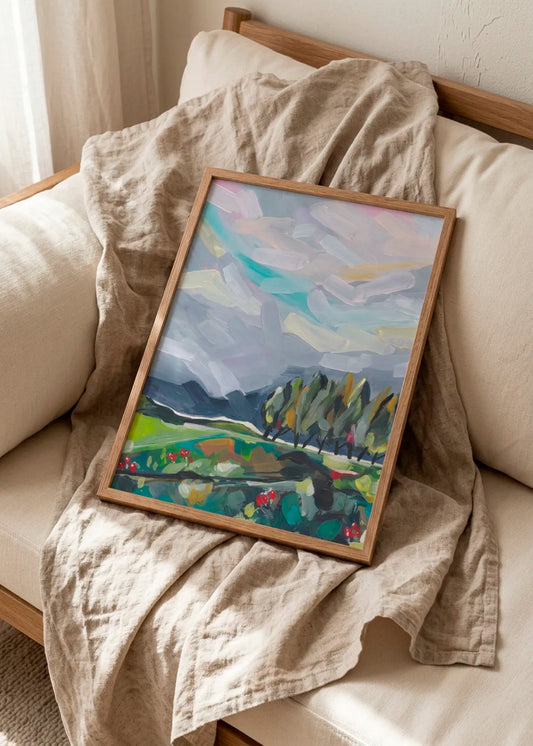 Colorful Abstract Landscape by Dirkie Nell – framed abstract landscape poster with soft blue-grey sky, green fields and colourful painterly details, styled on a light sofa with natural linen.