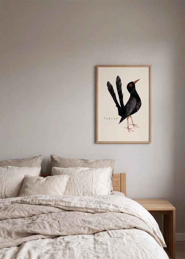 Elegant Black Thrush plakat af Josephin Hermsdorf i lys egetræsramme, stylet over en seng i et roligt soveværelse med lyse tekstiler og naturlige trædetaljer.
