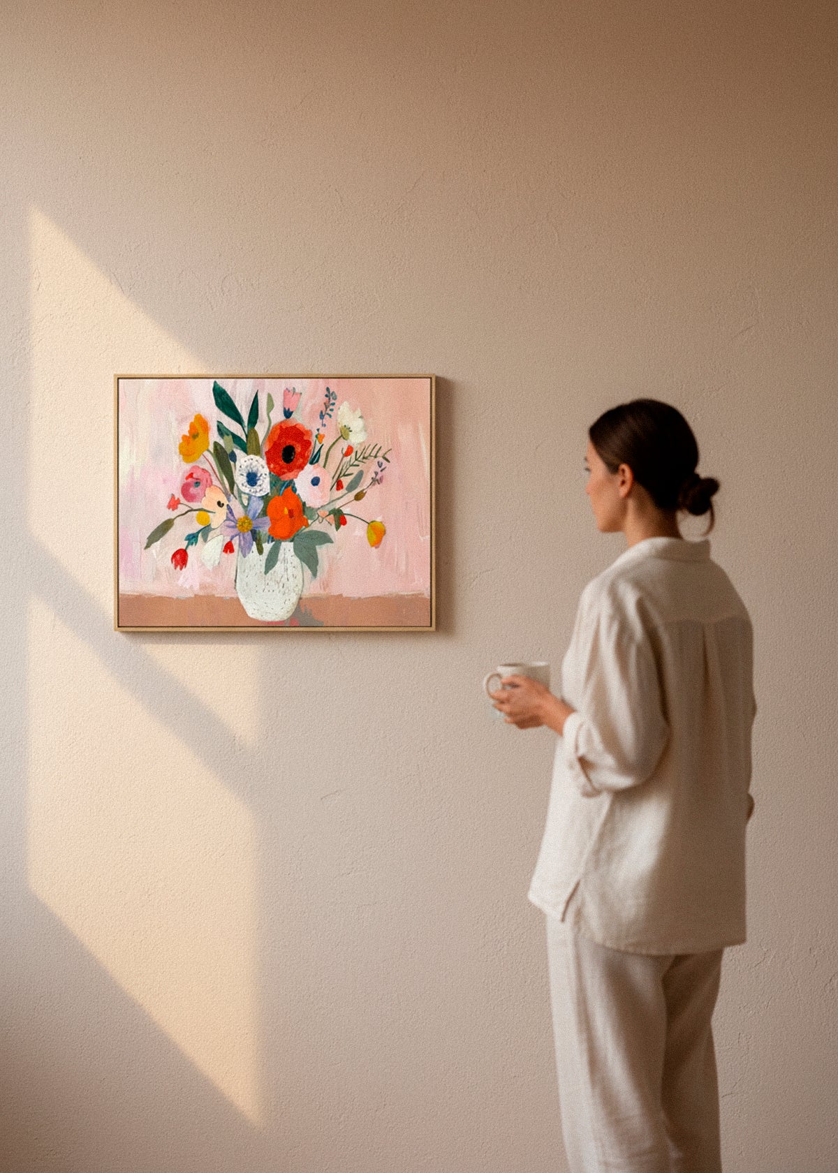 Flowers canvas print by Hello Poster featuring a colorful bouquet in a white vase on a soft pink background, displayed in a bright Scandinavian interior.