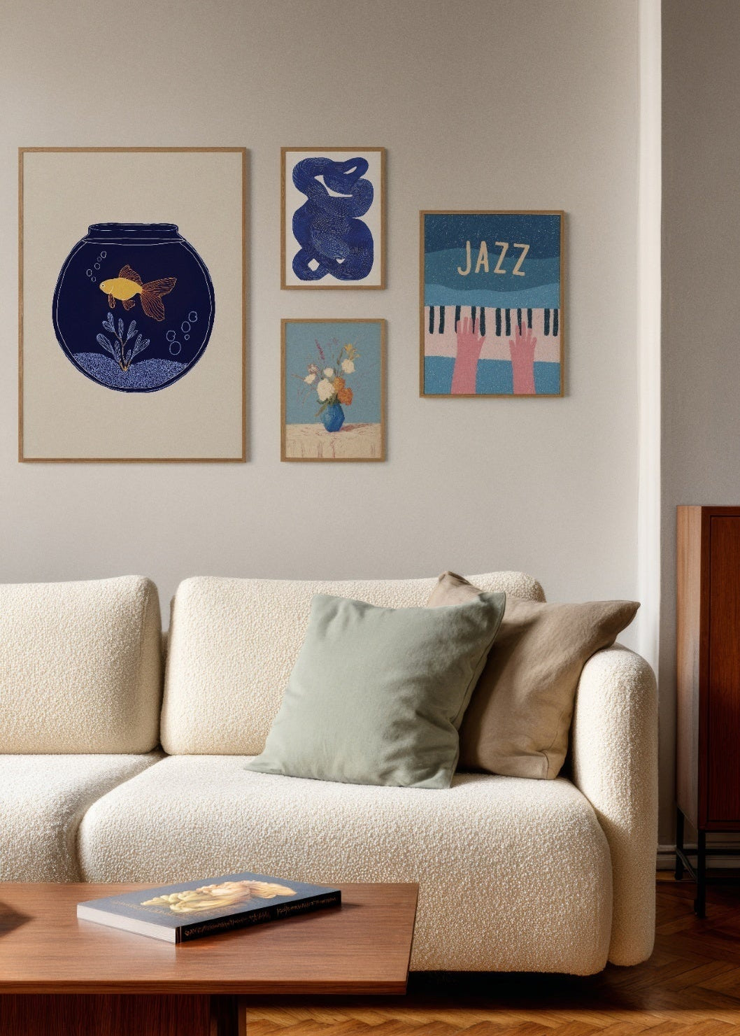 Modern gallery wall with blue-themed posters including a goldfish bowl illustration, abstract blue lines, a floral vase print, and a jazz-inspired poster above a cream sofa.