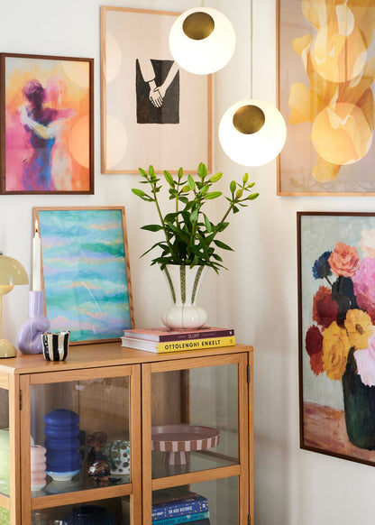 Colorful gallery wall with posters including Hold Me, Togetherness, Blossom and abstract designs, styled in Scandinavian living room with oak cabinet.