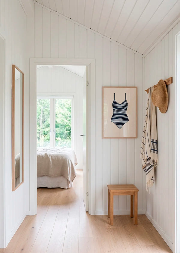 Striped swimsuit poster in oak frame styled in bright Scandinavian summer house hallway with wooden floor and natural light