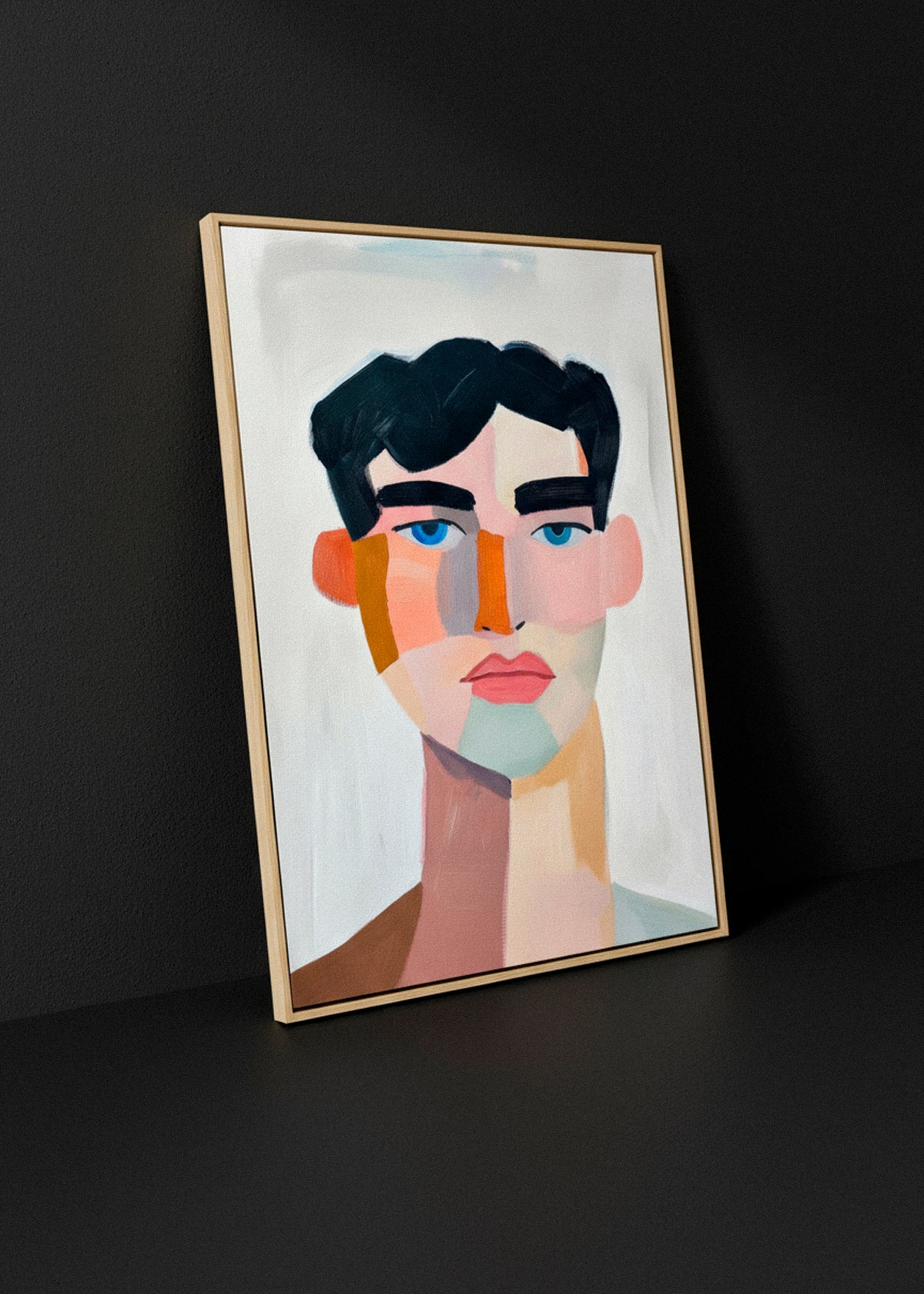 Canvas artwork “Male” leaning against a dark wall, framed in light wood, with soft studio lighting highlighting the abstract portrait.