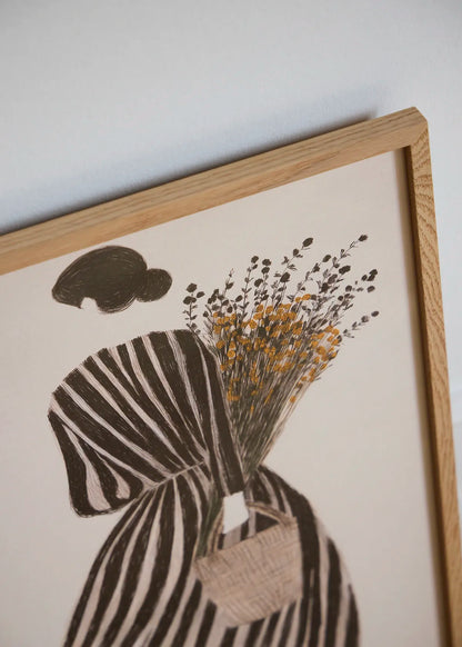 Close-up of MariGold floral art print showing a woman in a striped dress, delicate wildflowers and warm golden yellow details in an oak frame.