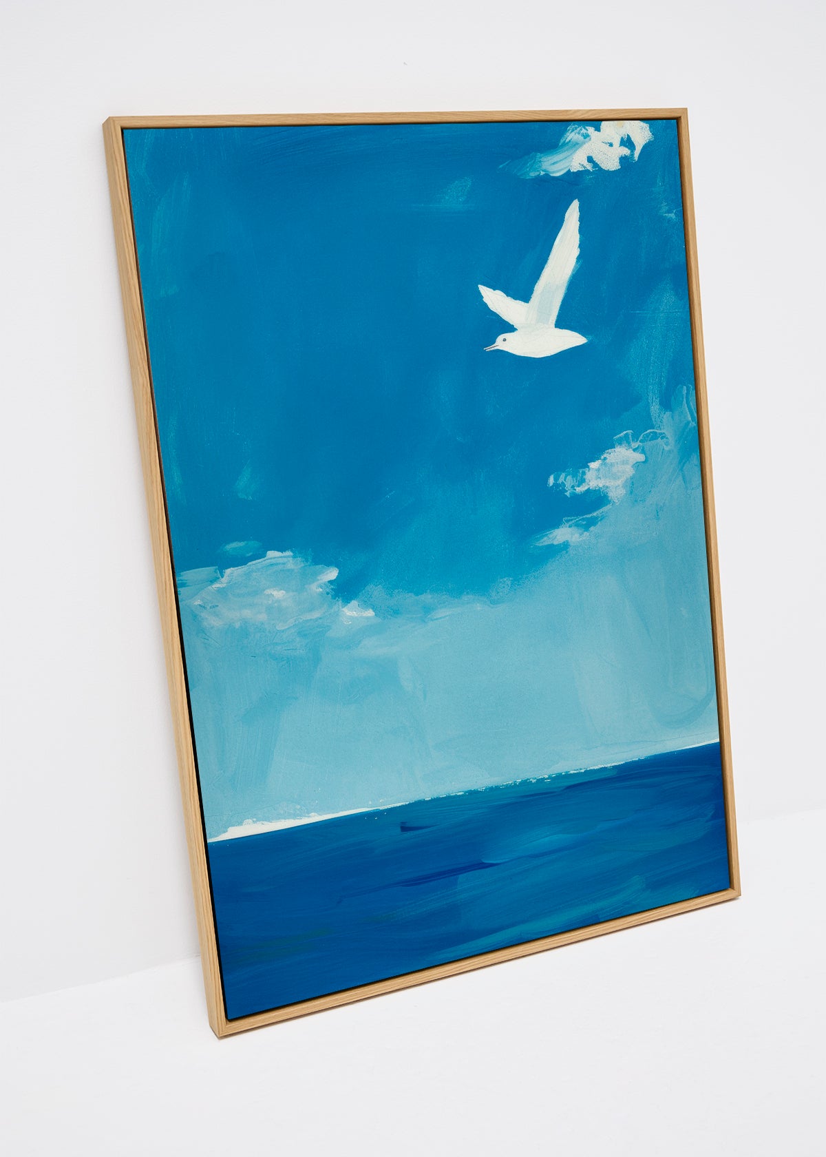 Ocean canvas print featuring a white bird in flight over calm blue sea and sky – modern wall art in peaceful tones.
