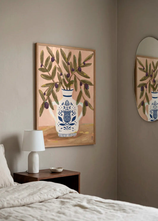 Olive Branches In a Pot Painting by Dirkie Nell – framed art poster with green olive branches, dark purple olives and a decorative blue and white ceramic vase, styled in a calm neutral bedroom interior.
