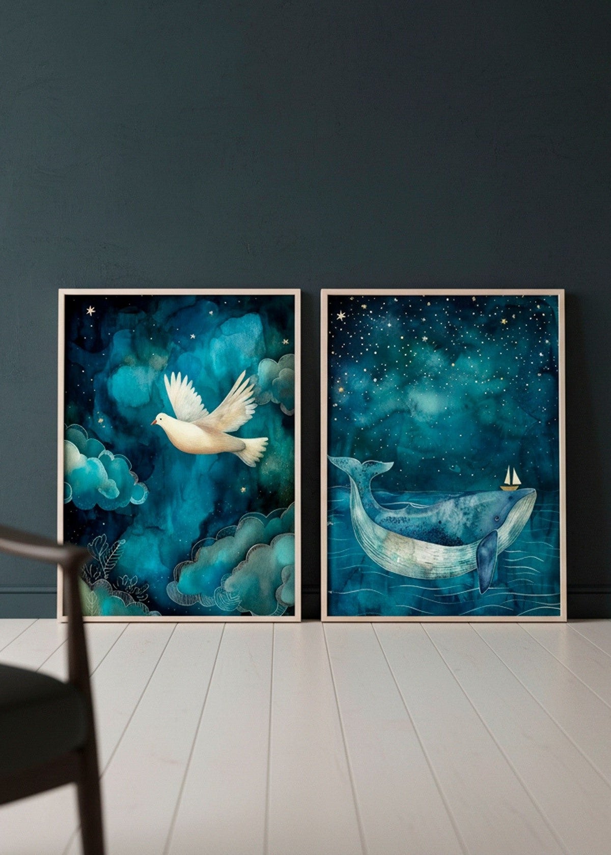Two large posters — a peaceful flying dove (One Small Friend) and a dreamy whale with a tiny sailboat (One Big Friend) — leaning against a dark teal wall in a minimalist Scandinavian room