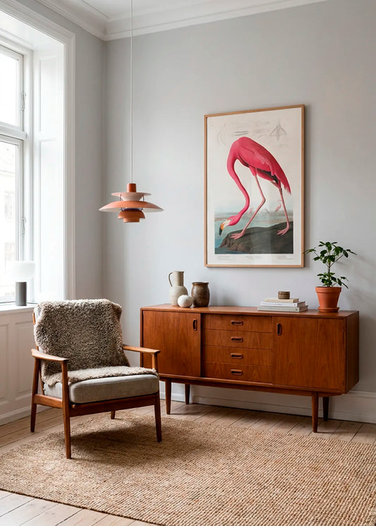 Indrammet flamingoplakat med en pink flamingo, hængt over en træskænk i en lys stue med nordisk retroindretning.