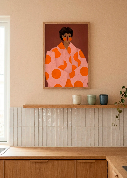 Polka Dot Fashion Portrait by Bea Müller displayed in a natural wood frame above a warm oak kitchen, styled with ceramic cups, soft beige walls and glossy white tiles.