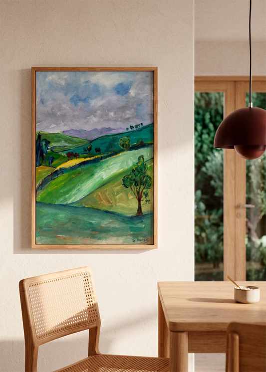 Rolling Green Hills by Sharyn Bursic featuring a painterly green countryside with rolling hills, scattered trees and a cloudy blue-grey sky.