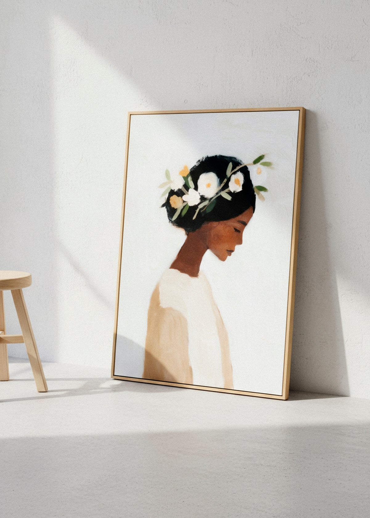 Framed “Saint” canvas print leaning against a light wall with a linen armchair and natural sunlight, evoking calm and grace.