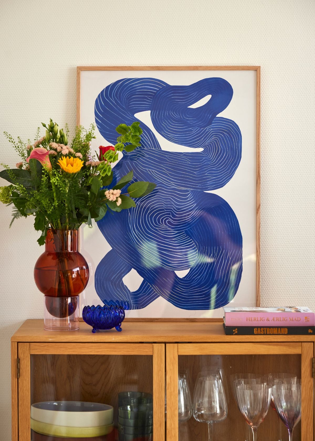 Detaljeret nærbillede af Shape No. 10 plakat med blå grafiske linjer på hvid baggrund, liggende på træbord med naturligt lys og skygger.