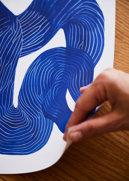 Hånd der holder hjørnet af Shape No. 10 plakat, som viser den blå abstrakte linjekunst på FSC-certificeret papir med mat overflade.