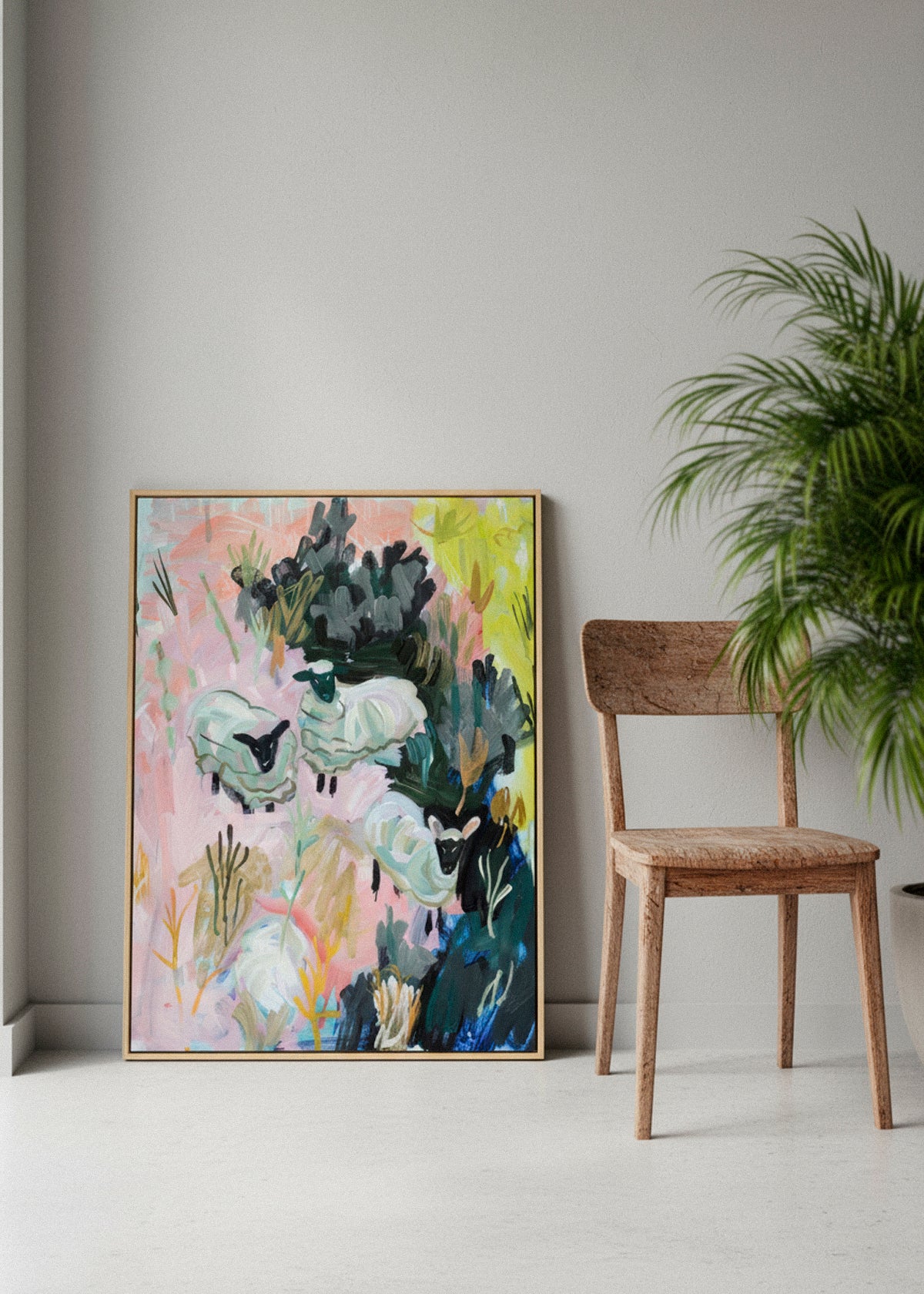 Framed “Sheep Farm” canvas print leaning against a wall on a wooden floor with wildflowers in the foreground.