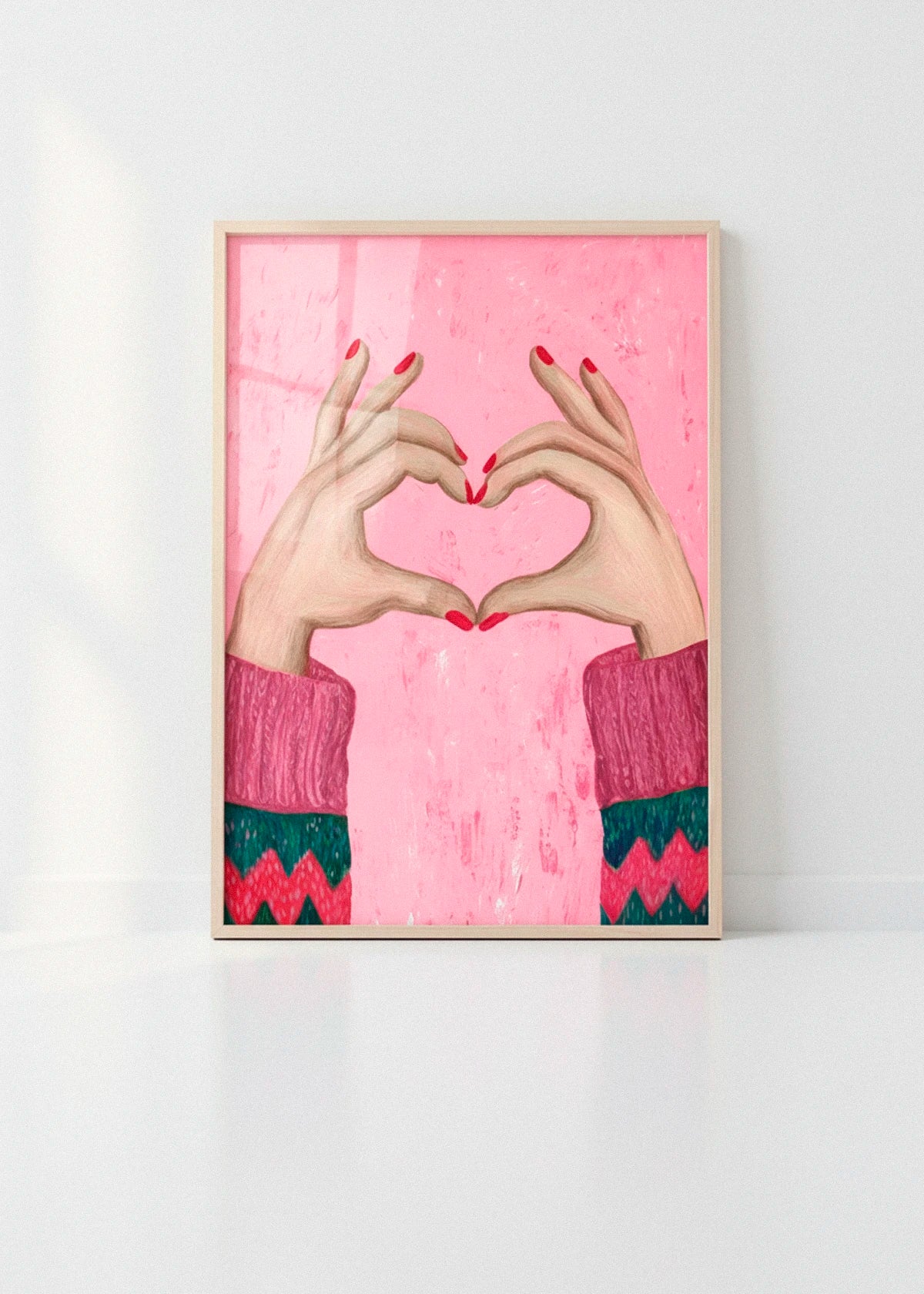 Sweater Love art print with pink background and heart-shaped hands, photographed in a bright minimalist interior with clean white walls.