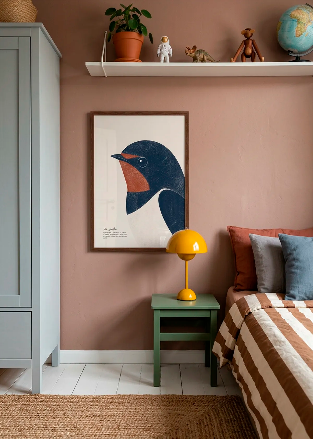 Minimalist Swallow Bird art poster by Ohkimiko displayed above a bedside table in a warm children’s bedroom with a dusty pink wall, striped bedding, green furniture and playful decor.