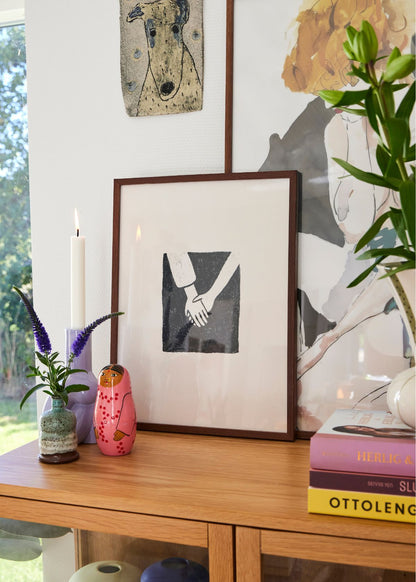 Togetherness poster in dark frame on a wooden cabinet, styled with candle, books, and colorful decor for a cozy Scandinavian home.