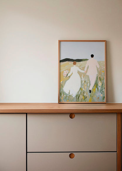 Us poster on a wooden sideboard – A romantic and dreamy art print depicting a couple in a field, adding warmth and elegance to a soft, neutral-toned interior.