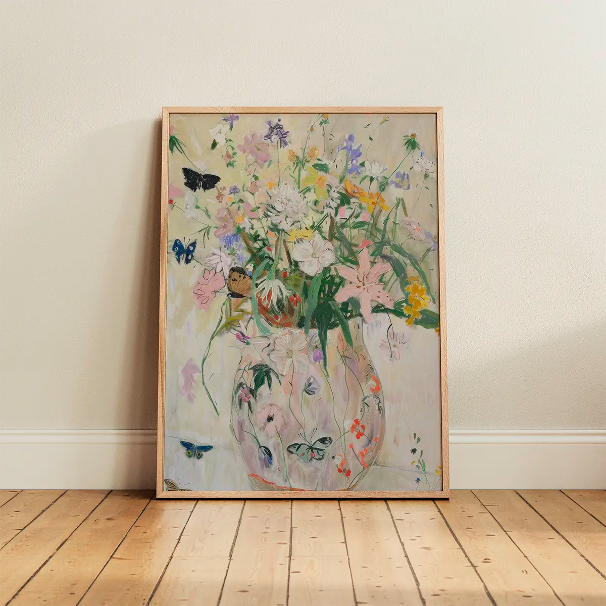 The ‘Wild Garden’ poster in an oak frame leaning against a light wall, featuring soft botanical and bird details in a Scandinavian interior