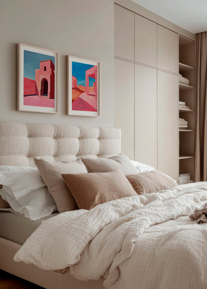 Cozy bedroom with neutral decor featuring two framed desert-themed art prints with pink and blue hues above a padded beige headboard, complemented by soft, textured bedding and beige pillows